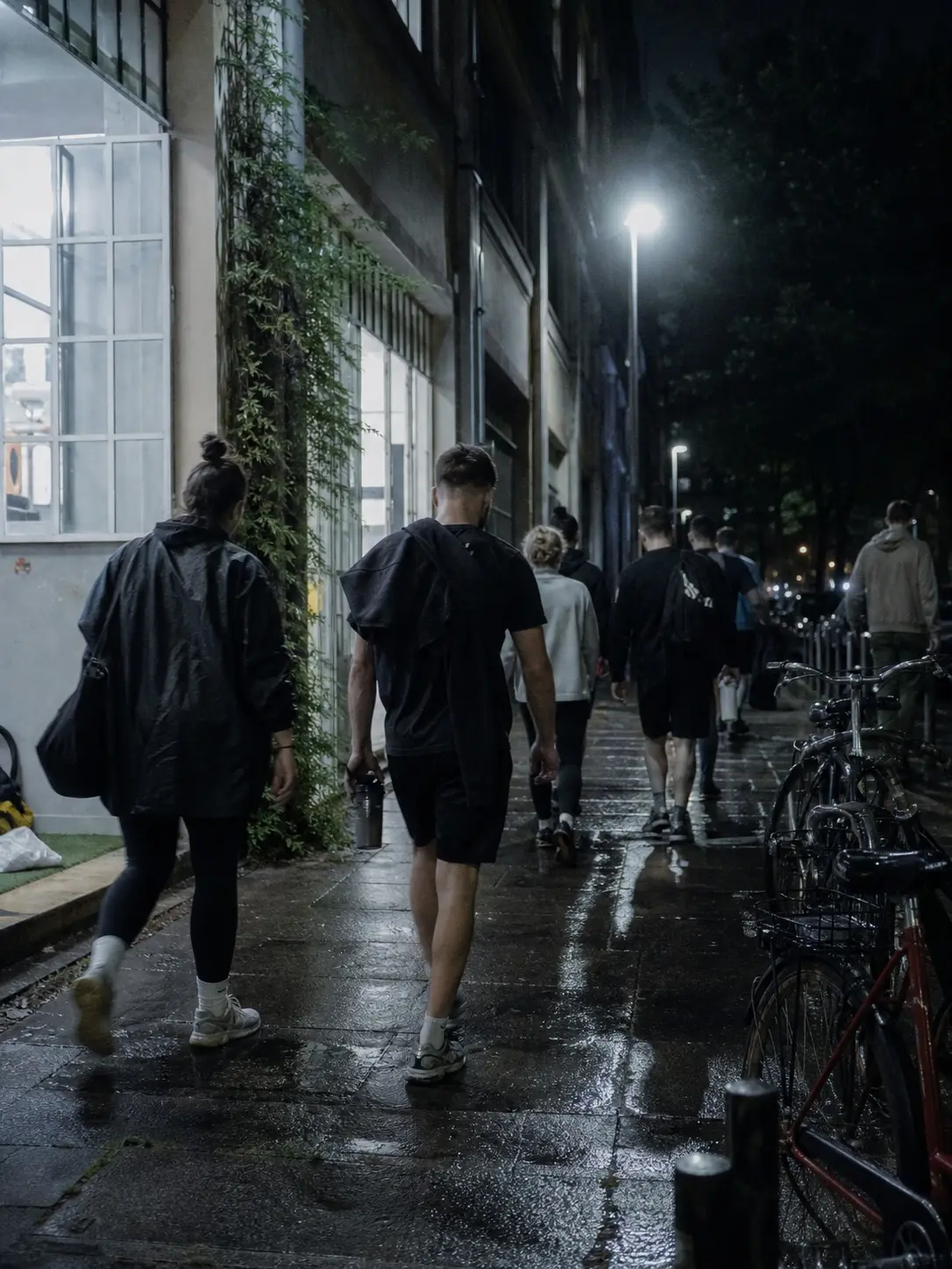 Gruppe verlässt nachts das Studio, Laternenlicht, Fahrräder